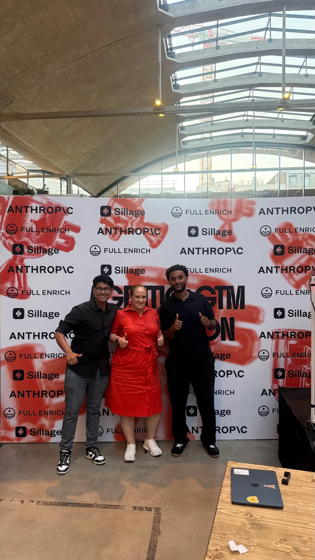 Three team members in front of the Agentic GTM Hackathon sponsor wall